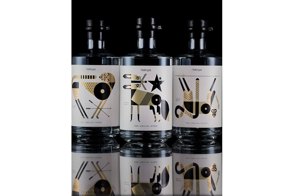三个深色瓶子，上面贴有白色标签，并在Roland DG UV 打印机上打印了彩色图形。