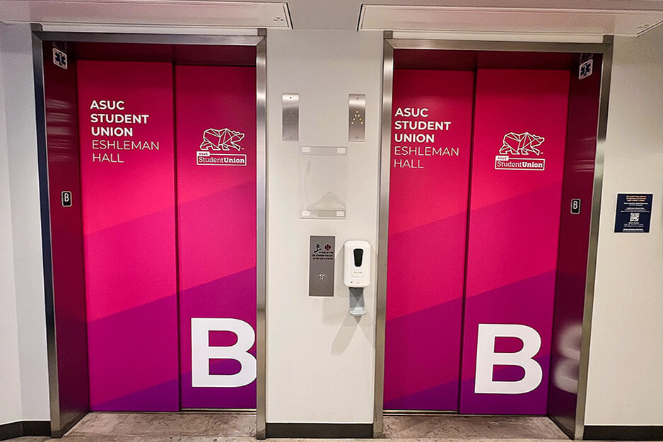 Duas portas de elevador envoltas em gráficos vermelhos e rosa impressos em uma impressora de tinta de resina AP-640.